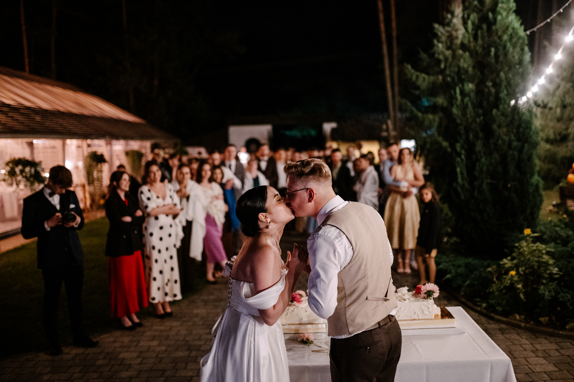 Karolina i Patryk krojący tort weselny podczas przyjęcia w gronie gości
